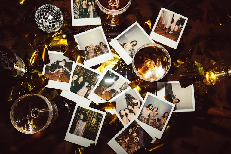 A collection of polaroid photos and glasses on a festive table, capturing party memories.