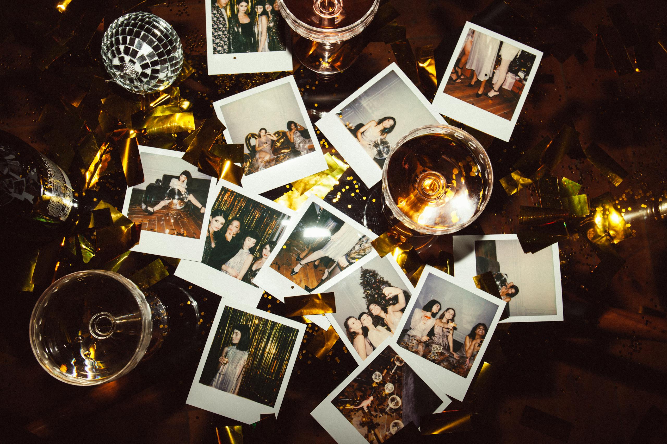 A collection of polaroid photos and glasses on a festive table, capturing party memories.
